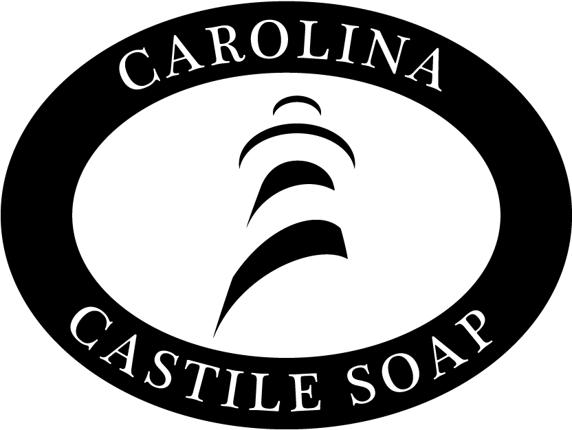 white logo with black circle and text. Text reads "Carolina Castile Soap" and inside the circle is a striped light house.