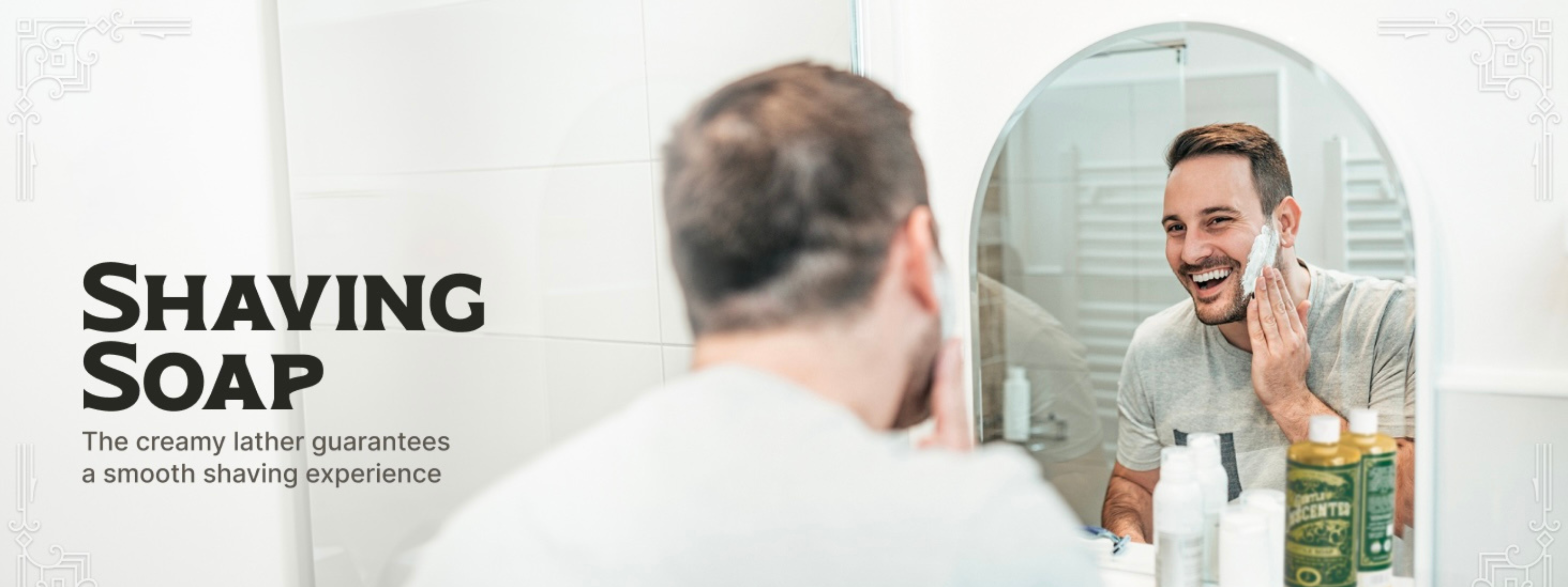 man applying soap to beard in preparation for shaving while looking in the mirror and smiling. A bottle of Gentle Unscented Castile Soap sits in front of him at the mirror.